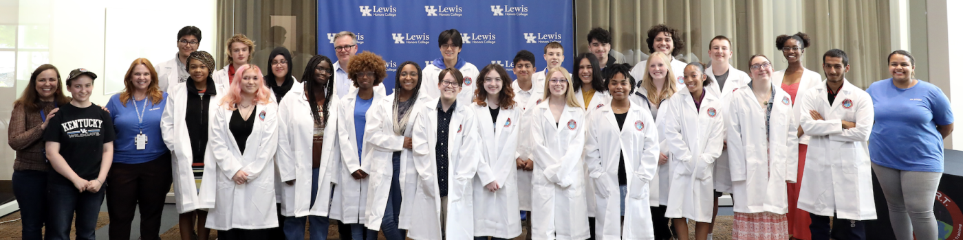 dr. luke bradley and a recent cohort of students, all dressed in lab coats