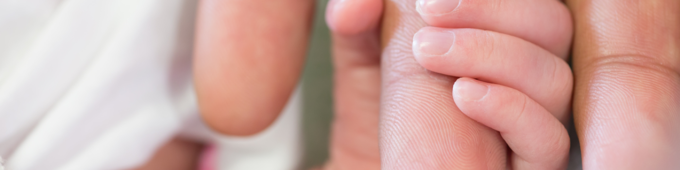 Newborn hand holding finger
