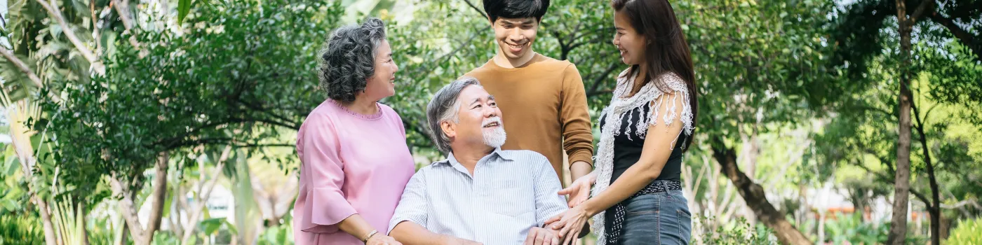 An elderly man sitting in a wheelchair surrounded by his family. 