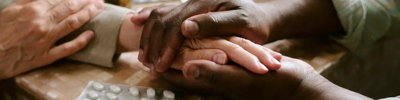 Caregiver is holding hands with an elderly patient, providing comfort. 