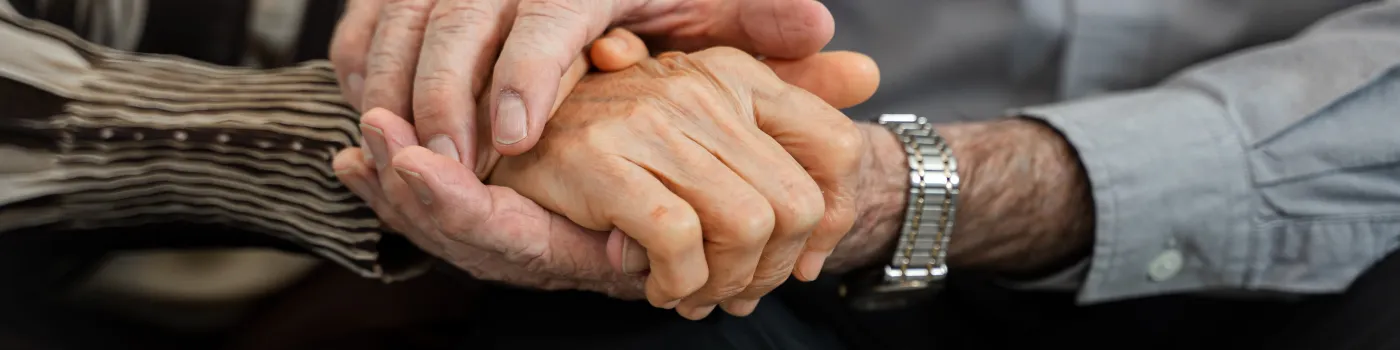 Close-up picture of a senior couple holding hands. 