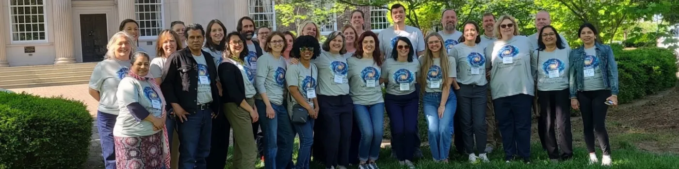 Group of people in matching grey shirts standing outside