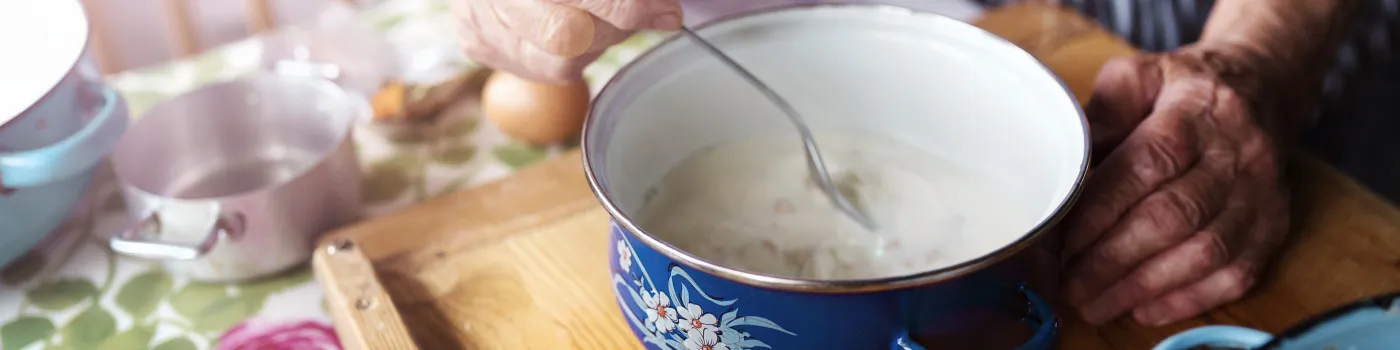 Close up on an elderly woman's hands stirring a bowl of food. 
