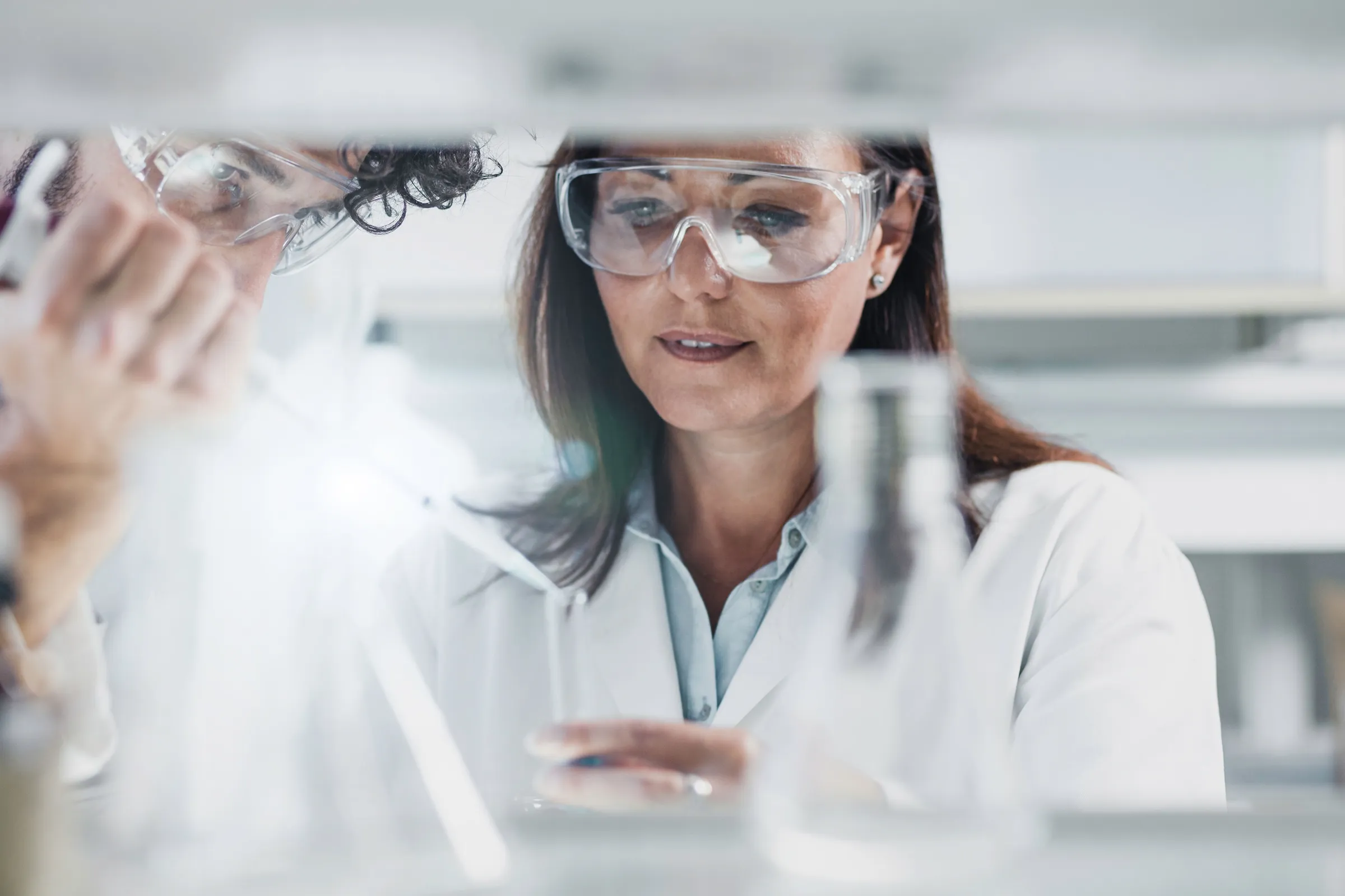 two researcher close together in a laboratory with beakers in foreground