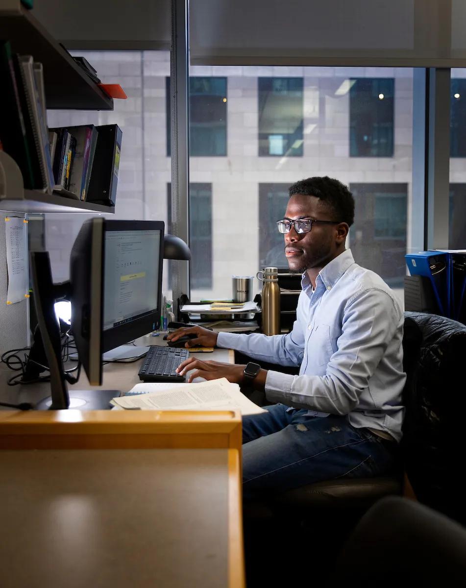 researcher siting at desk in front of desktop monitors