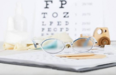 Glasses on a notepad with a sight chart in the background