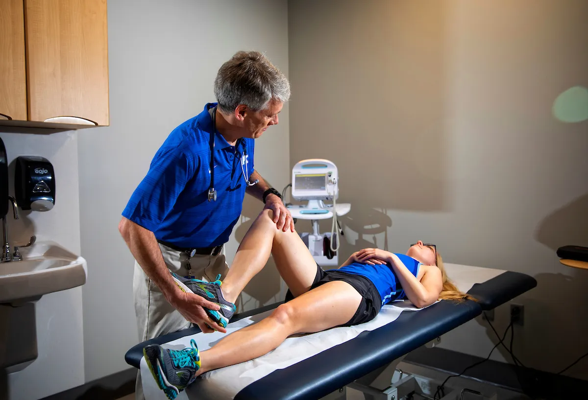 patient laying on exam table and doctor manipulating patient's knee