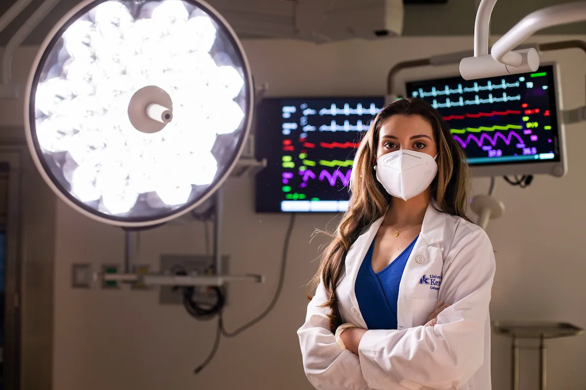 medical student in surgery suite with bright surgical light and monitor in background