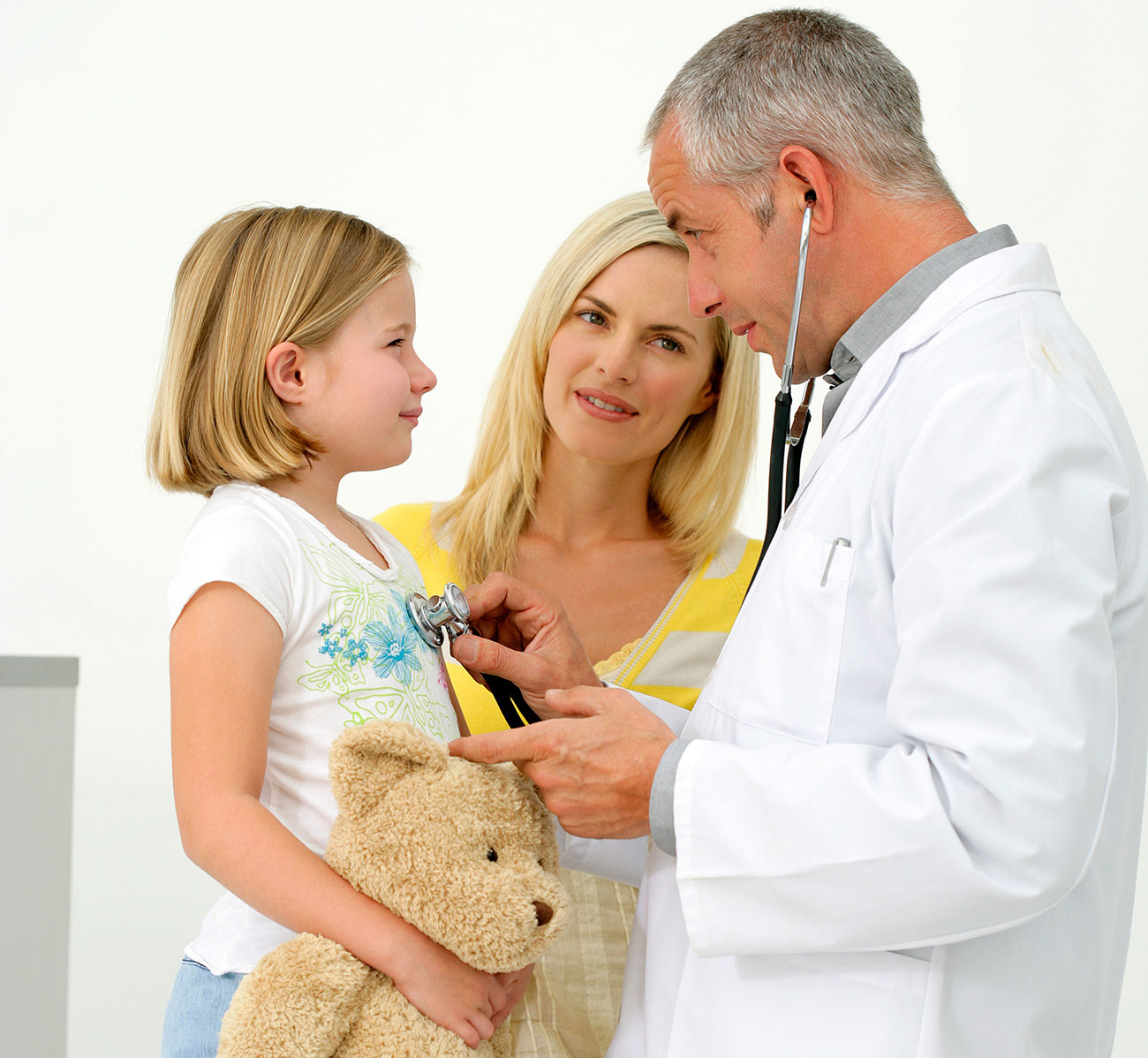 doctor listening to child's heart with stethoscope; parent standing in between