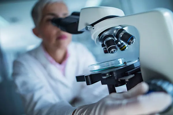 microscope in foreground; researcher in background