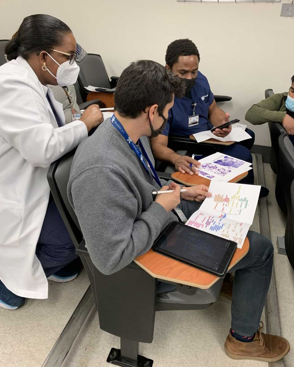 Drs. Juanita Ferreira, Andre Ene, and Emmy Mbagwu assess cytologic features of a soft tissue tumor during a team learning experience.