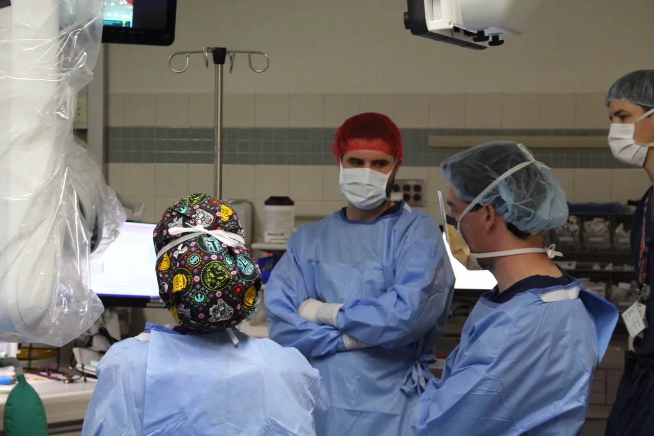 Blue scrubbed residents standing around a surgery.