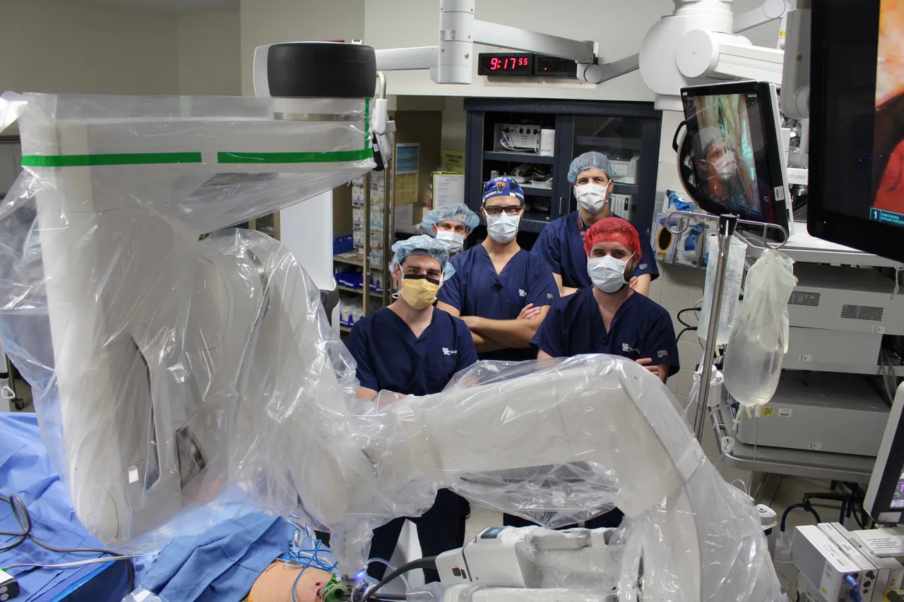 A group of scrubbed doctors standing behind a piece of hospital equipment. 