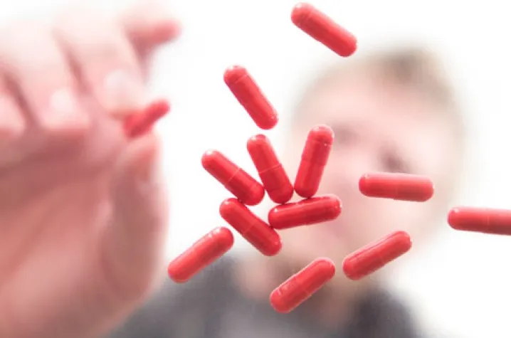 Man reaching towards a scattering of red pills