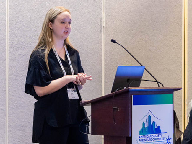 Katie Colson presenting behind a lectern at the 2024 American Society for Neurochemistry Meeting