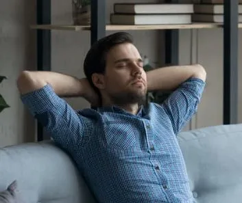 Man eyes closed blue shirt arms behind head, breathing