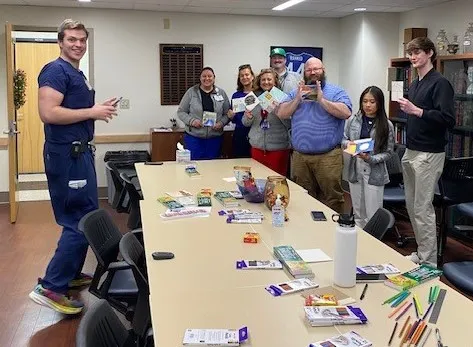 Group of staff members smiling and showing their colored tile from colors and connections
