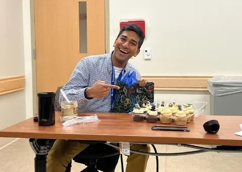 Rahul, a NICU resident, sitting at ta table with cupcakes and gifts.