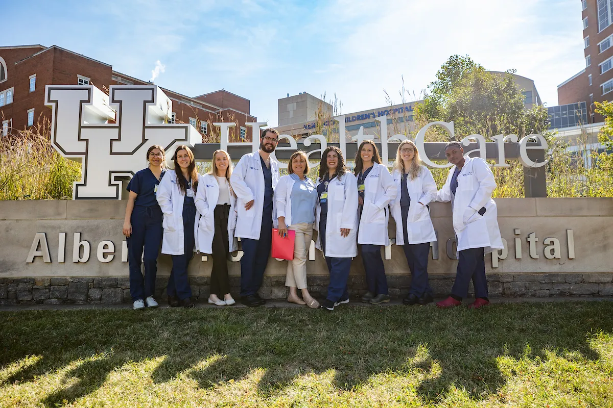 a group of uk college of medicine residents in scrubs and white coats stand in front of the uk chandler hospital