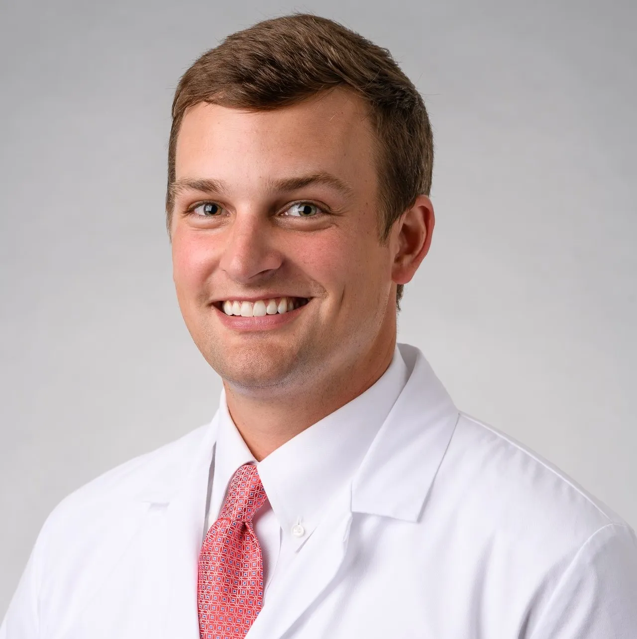 Sam Hughes smiling in his white coat