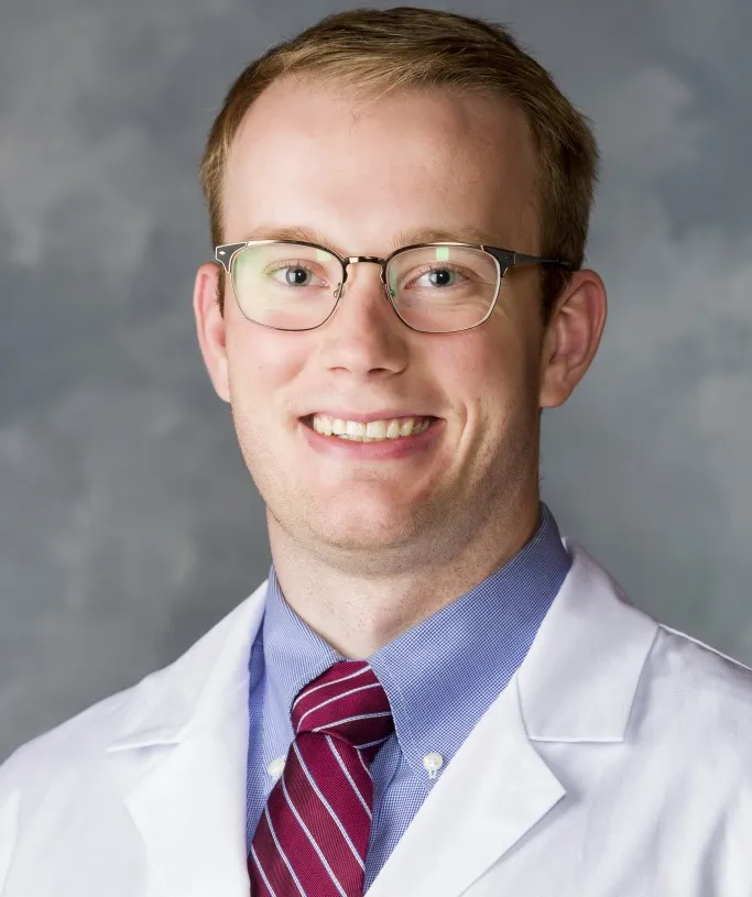 Garrett Oberst posting for headshot in white coat
