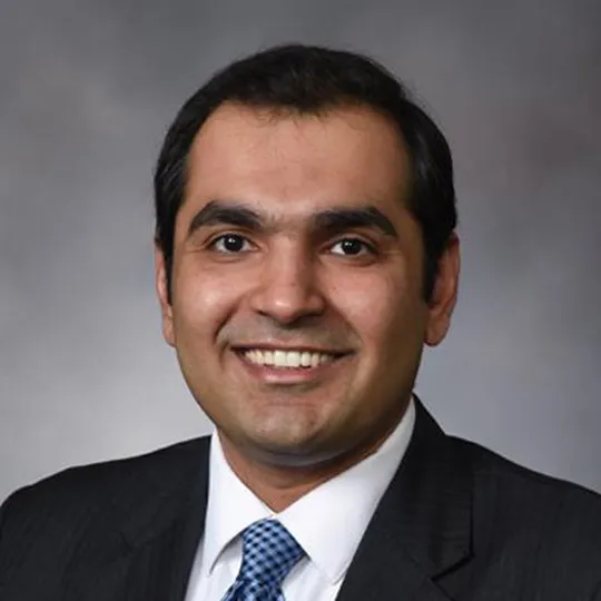 Malik Khan in black suit and blue tie.