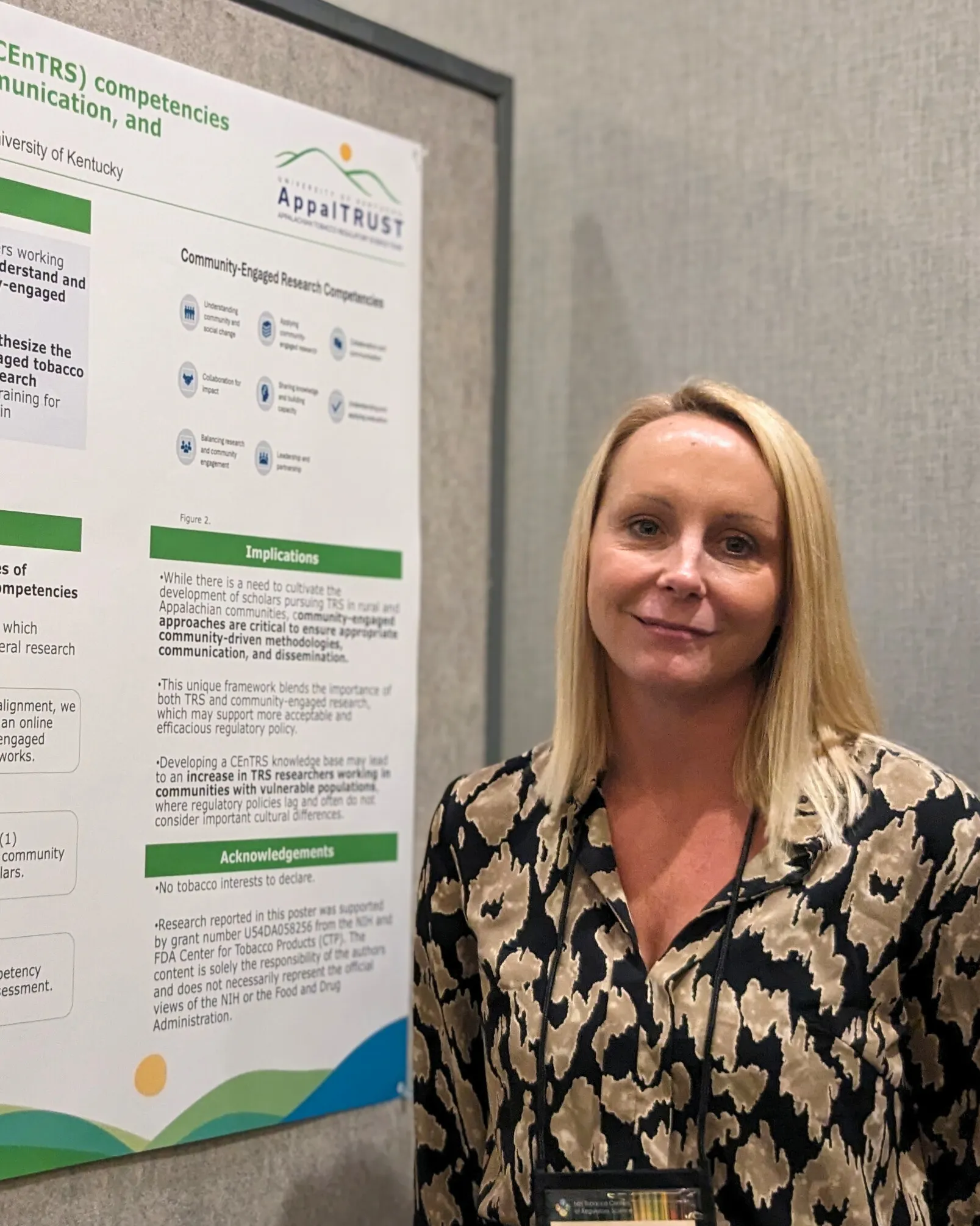a blonde woman standing next to an academic poster