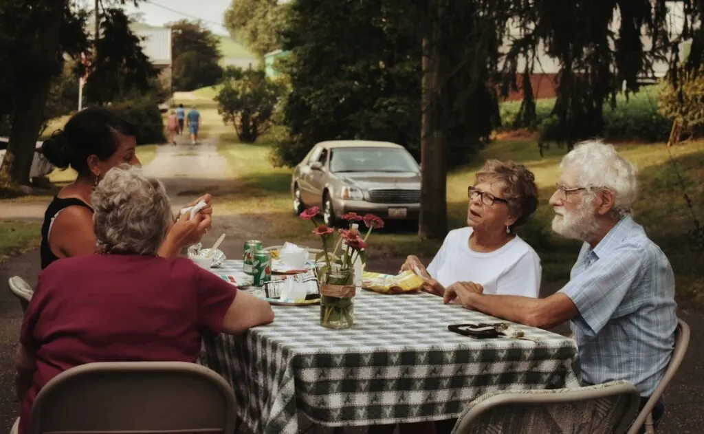 A group of elderly individuals sitting at a farm table enjoying a meal.
