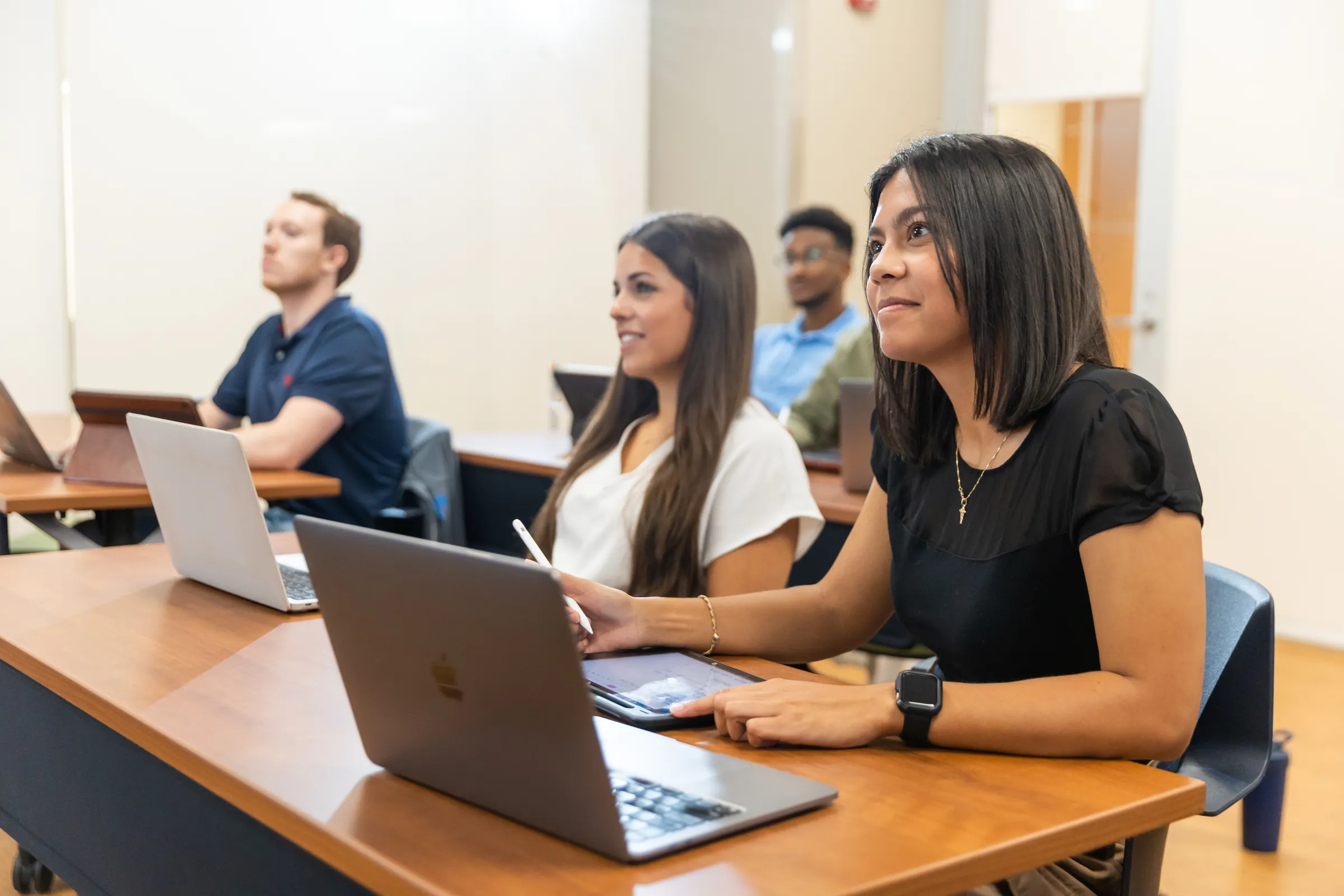 Students on laptops listening to a lecture