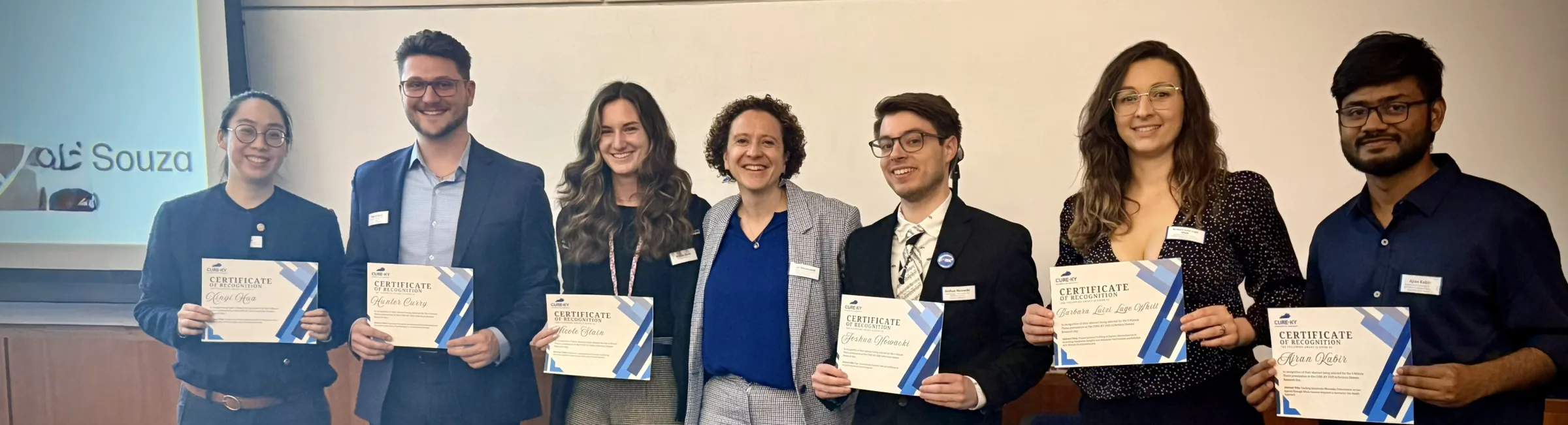 Six students holding certificates for their participation in the 2025 ID Day 3-minute thesis presentation. The students are accompanied by Dr. Ilhem Messaoudi, Chair of the CURE-KY consortium. 