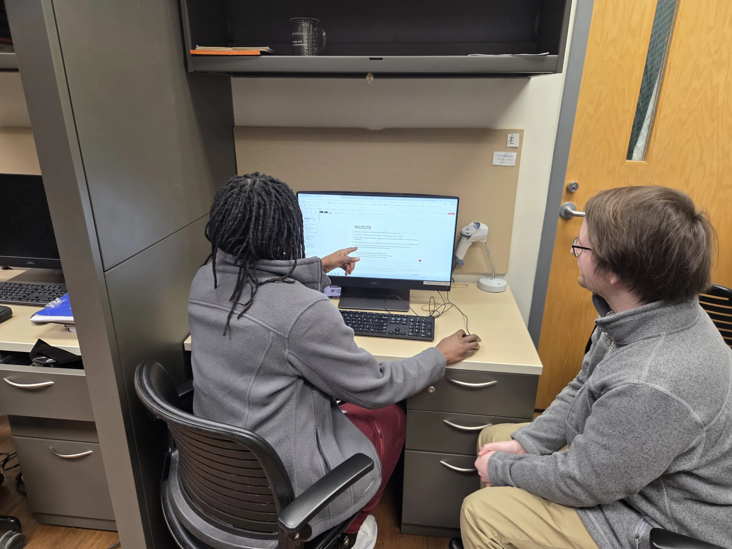 Two residents study content on a computer screen. 