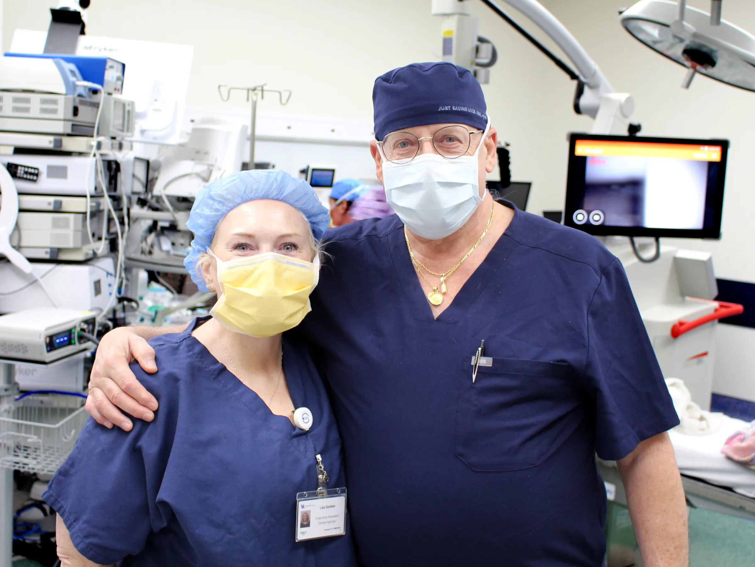A close up of two people scrubbed up smiling through masks in the OR