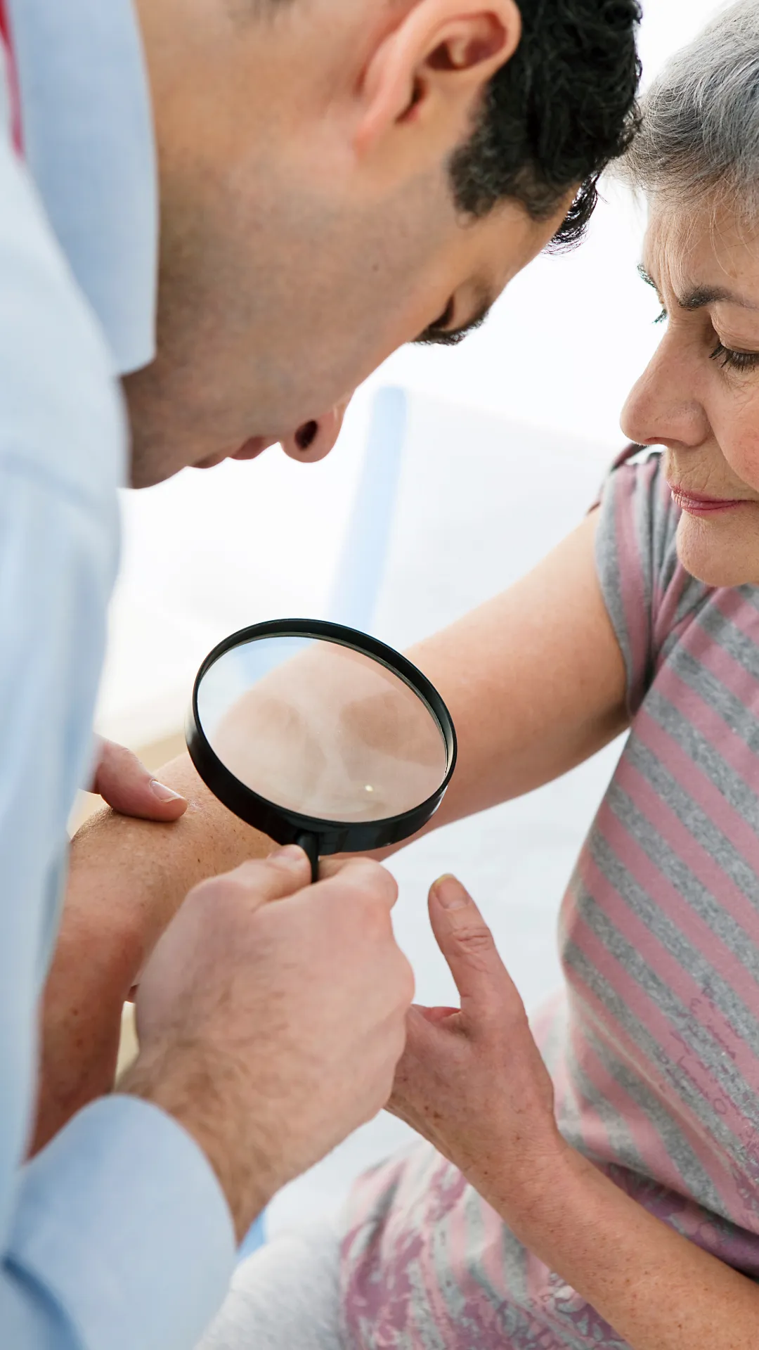 Man with a magnifying glass looking at a woman's arm