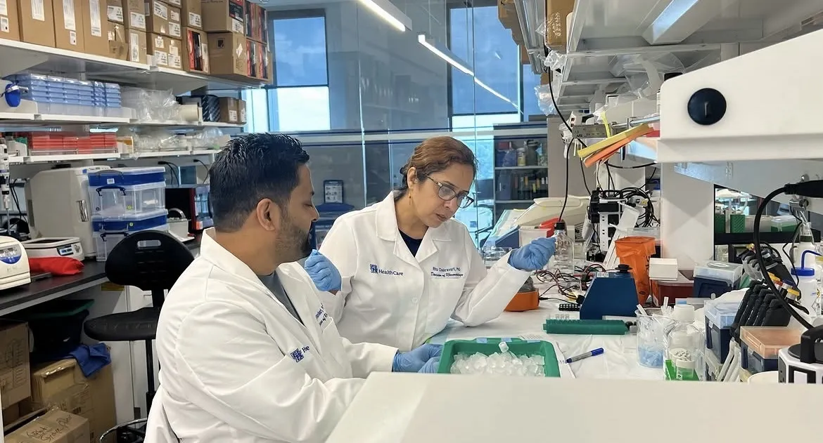 Dr. Chakravarti works in the laboratory in her white coat with a member of her team