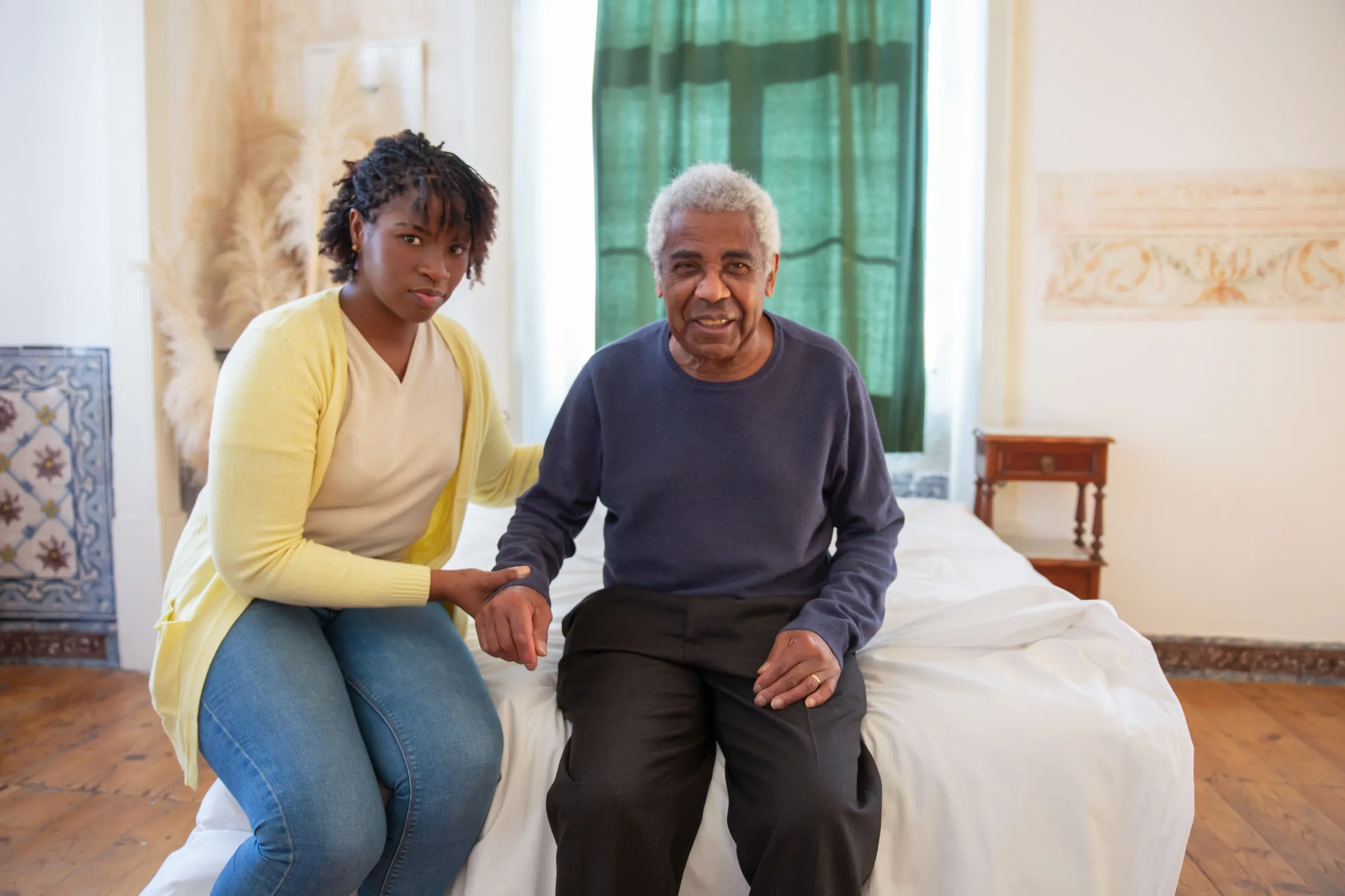woman and father seated at edge of bed