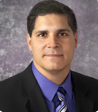 Doctor Michael Singh in blue blazer, dark blue shirt, and tie