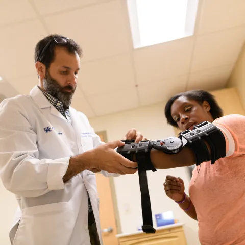 Doctor helping patient with an arm brace