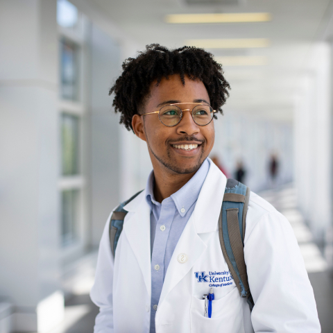 person in a white medical coat smiling and looking to the side