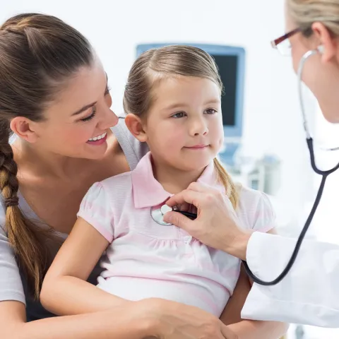 Little girl with her mother, and having a doctor check her heartbeat.