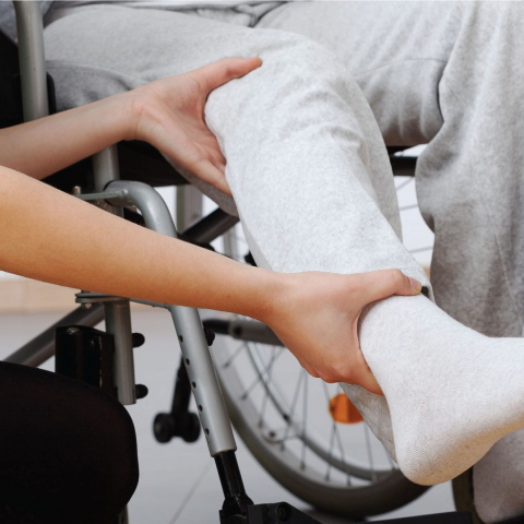 Doctor assisting patient in wheelchair with physical therapy on their lower leg