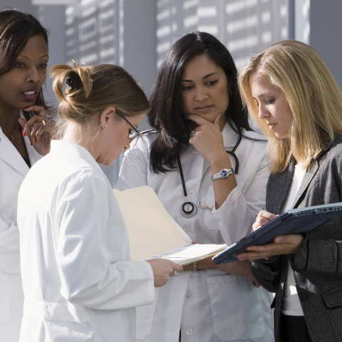 four health care providers consulting with each other while review a chart