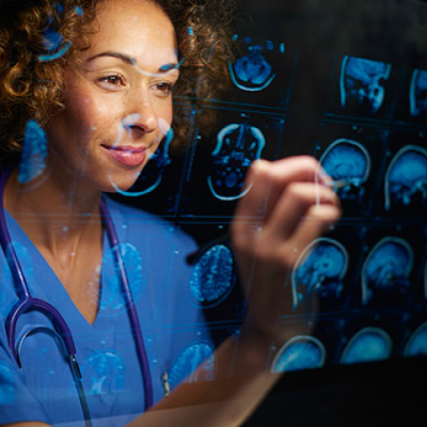 medical provider writing on a clear screen with images of human brain
