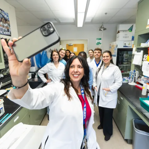 a research professor taking a photo with her lab staff members and students