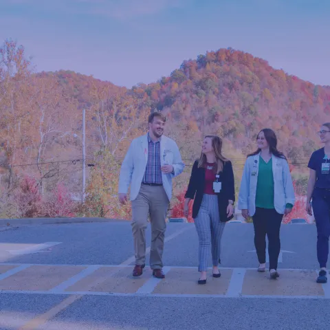 four students walking down the street with mountains behind them