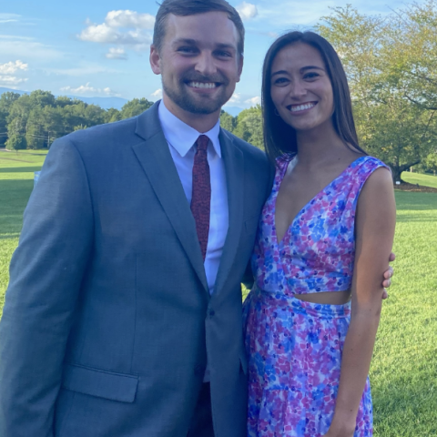Sam Hughes standing with his wife dressed nicely and smiling at the camera