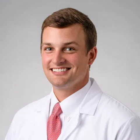 Sam Hughes smiling in his white coat