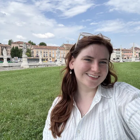 Student standing outside with statues and buildings behind her