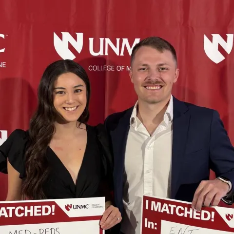 Madison Han and a male student on match day at UNMC. Madison holds a sign that says, "I Matched! Med-Peds program at the University of Kentucky." The man's sign says, "I matched! ENT program at Kentucky"