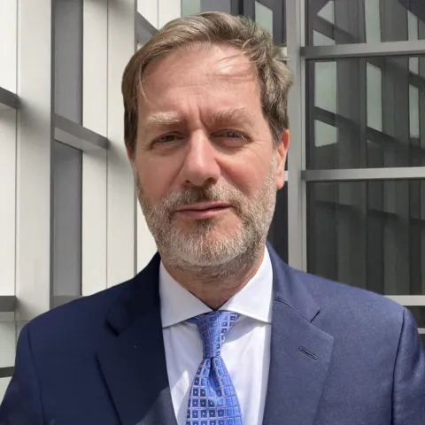 Dr. Pierluigi Porcu stands for a headshot in a blue coat and tie