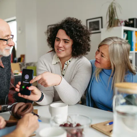 Family is assisting elderly grandparents on how to operate a phone. 